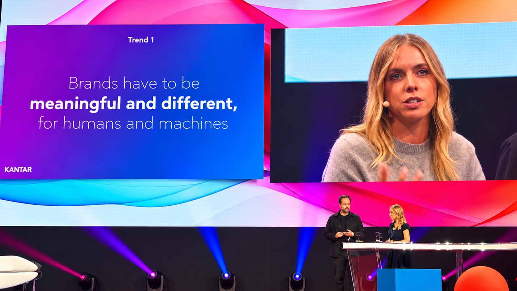 Original-Praesentationsfolie mit dem Text 'Brands have to be meaningful and different, for humans and machines', Trend 1, im Hintergrund die Sprecherin auf der Buehne