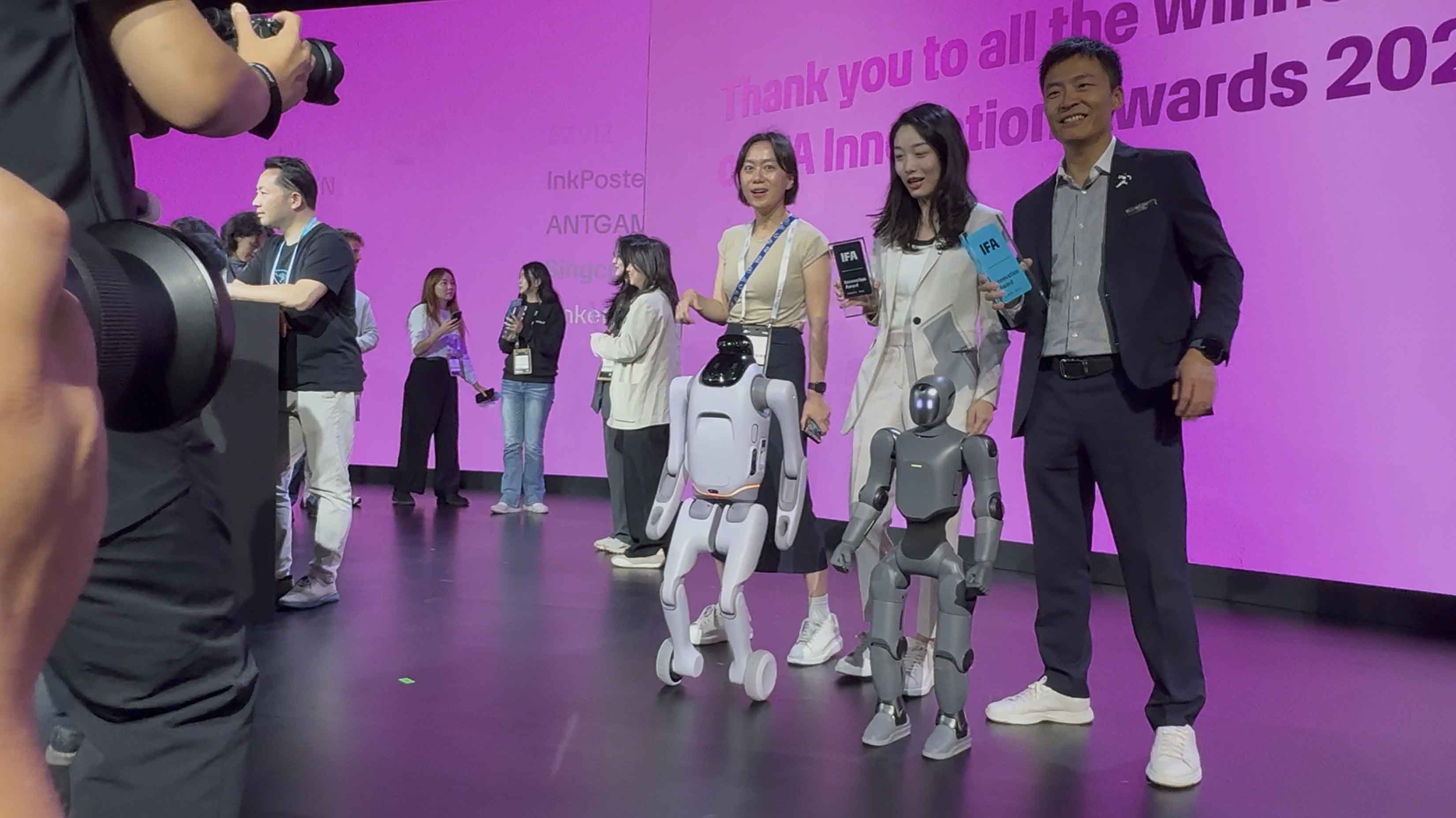 Bühnenprojektion mit dem Schriftzug IFA Innovation Awards in Verlaufsfarben von Pink zu Lila, davor zwei Moderatoren auf der leeren Bühne der Innovation Stage im CityCube Berlin